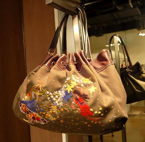 カーキ色のバッグ（５，９９０バーツ） <br>
一針一針、丁寧に縫われた刺繍の絵が可愛いバッグ。ころんと丸い形もキュート。荷物も見た目以上に入ります。色違いで黒も有り。 