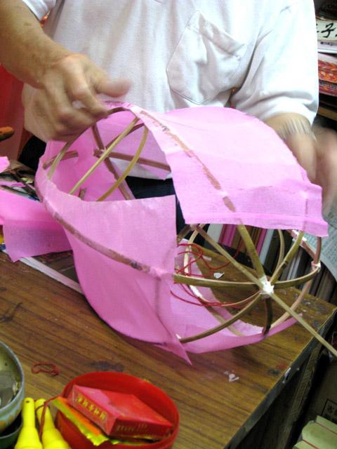 骨組みに沿って、色紙を張ります。竹の骨組みの外側に金色の紙を張っていきます。