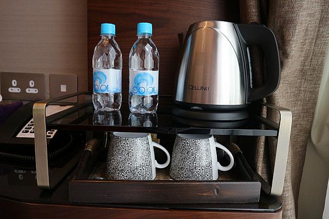 窓側の小さなデスクには、水やポットが置かれています。