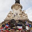 三色旗と花に囲まれたマリアンヌ像。色んな思いで人々が集まっています。