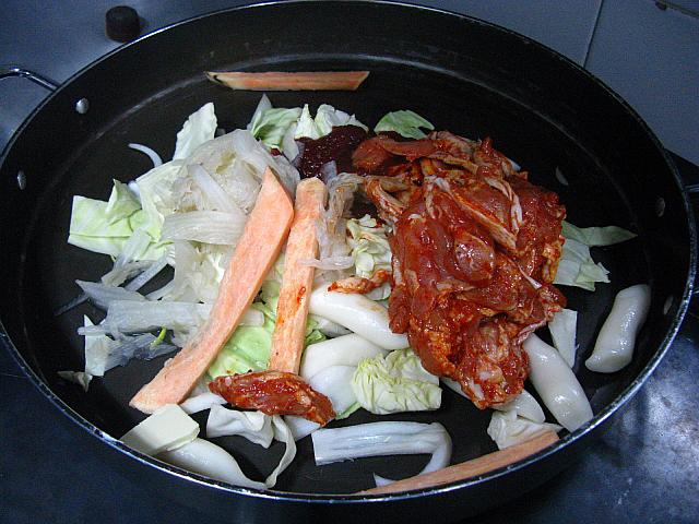 １．油をしいた鉄板に切った野菜と戻した餅などの具、下味を付けておいた鶏肉、残りのヤンニョム（薬味）をのせ、