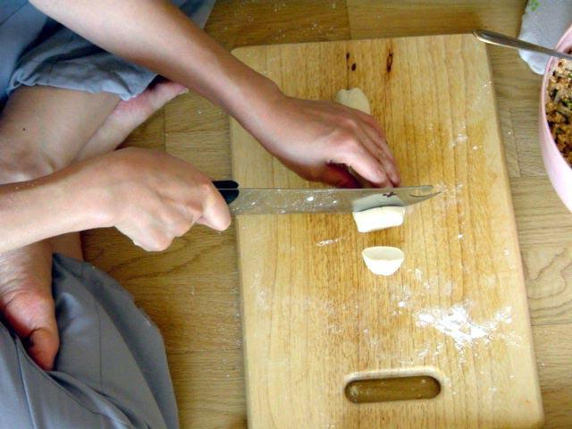 ２）生地は腕ひとつ分ぐらいの柱型に形を整えたあと、包丁で分量ごとに切っておきます。