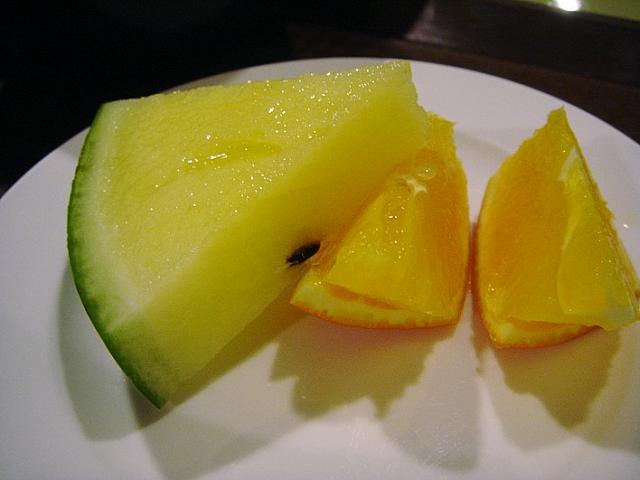 フルーツ。黄色いスイカとオレンジ。オレンジは食べやすいように切り込みが入れられています。