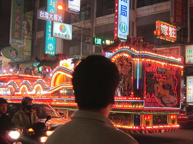 今回はすごい！大きな電飾に覆われた山車が何台も連なってやってきました！あ然と見送る通行人たち。