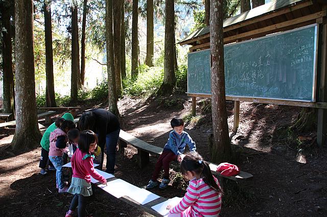 幼稚園生たちが、葉っぱを画用紙にこすっています