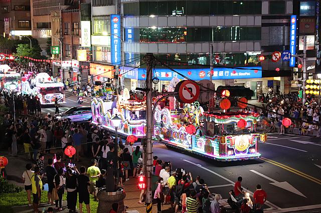 信号待ちをする花車の間を抜ける自家用車