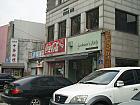 ２００ｍほどそのまま行き、道路の向かい側に渡ると、中華料理店の看板と、手前に花屋（※2011年5月現在）があります。