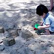 子供たちは日陰で砂のお城を作っています。